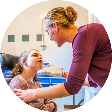 Photo of carer smiling at at young woman in a wheelchair