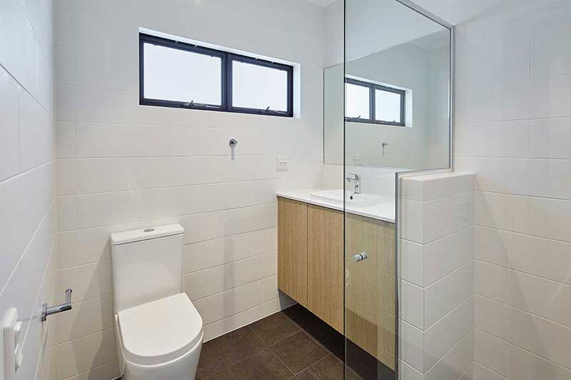 New shower room with white wall tiles, vanity and toilet.