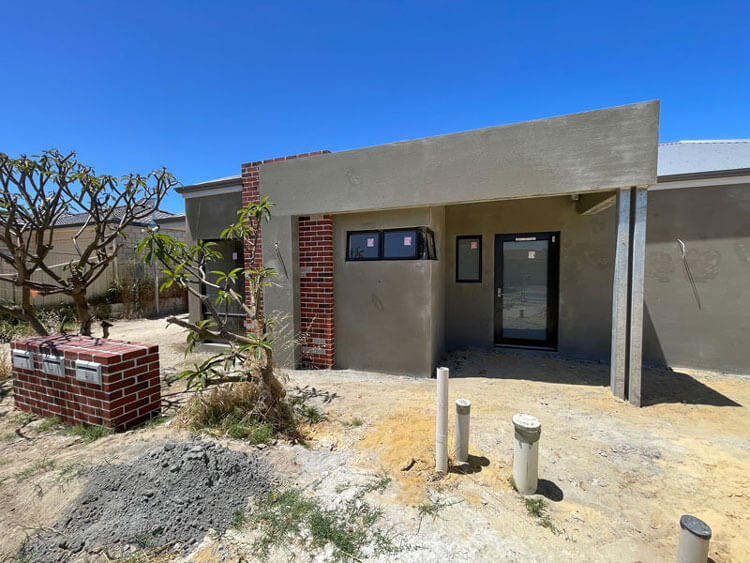 Front-facing NDIS villa 'a' at lockup stage. Shows brick and render not yet painted.