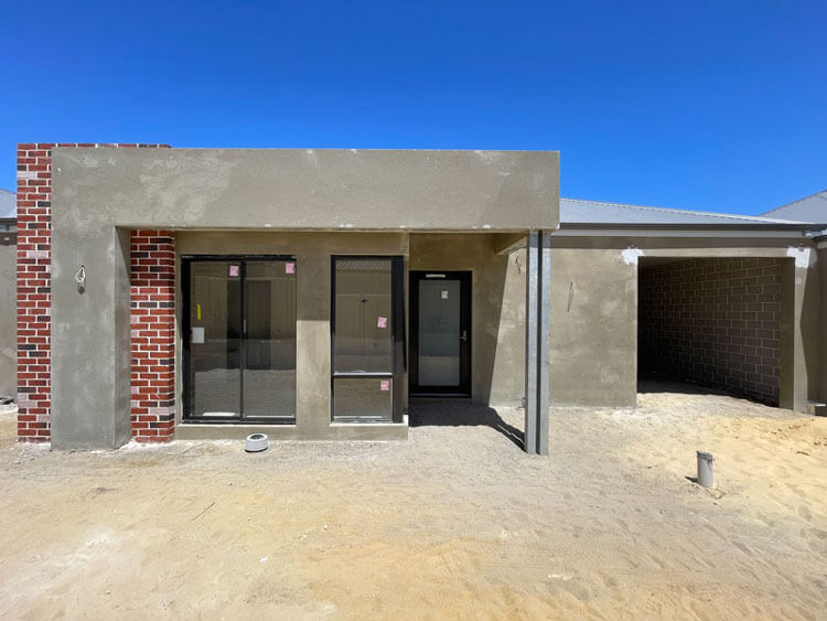 Middle NDIS villa showing unpainted render and brick facade.Black windows installed and property at 'lockup' stage.