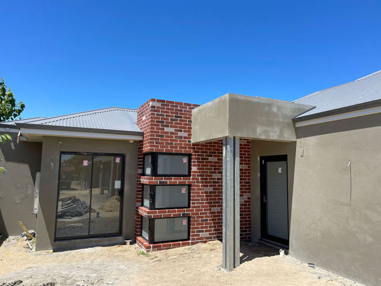 Rear NDIS villa showing unpainted render and brick facade.Black windows installed and property at 'lockup' stage. 